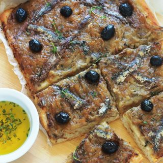 La pissaladière, une recette niçoise avec une pâte à pain ou à pizza, oignons confits et ail, anchois et olives, des herbes aromatiques. Un régal pour les amateurs d’oignons et d’anchois. Dégustez-la chaude ou froide. Avec une petite salade, cela vous fait un bon plat complet.