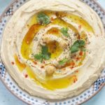 Houmous traditionnel authentique - purée de pois chiches au tahini. Dip santé prête en 5 minutes. Pois chiches, crème de sésame ou tahini, ail et jus de citron. dans une assiette