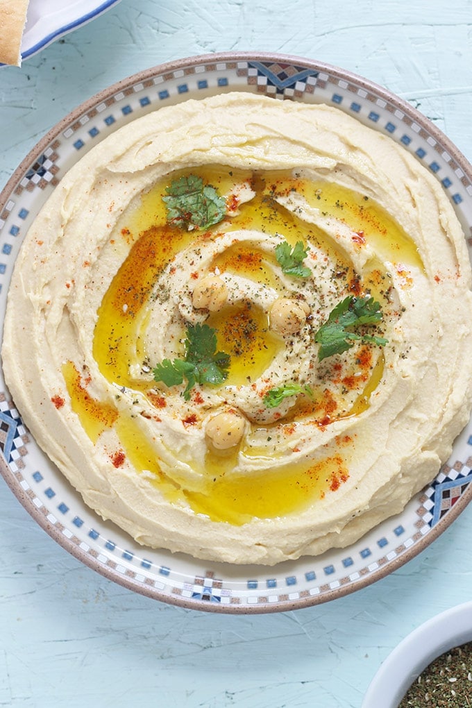 Houmous traditionnel authentique - purée de pois chiches au tahini. Dip santé prête en 5 minutes. Pois chiches, crème de sésame ou tahini, ail et jus de citron. dans une assiette