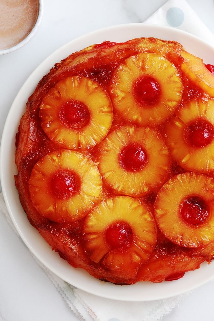 Délicieux gâteau au yaourt renversé à l'ananas et cerises confites caramélisés. Une variante classique à base de la fameuse recette du gâteau au yaourt. Très moelleux et facile à faire. Vous pouvez le réaliser avec de l'ananas en boîte (coupé en tranches ou en dés) ou encore de l'ananas frais. Pour le goûter ou en dessert.