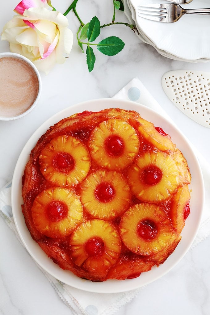 Délicieux gâteau au yaourt renversé à l'ananas et cerises confites caramélisés. Une variante classique à base de la fameuse recette du gâteau au yaourt. Très moelleux et facile à faire. Vous pouvez le réaliser avec de l'ananas en boîte (coupé en tranches ou en dés) ou encore de l'ananas frais. Pour le goûter ou en dessert.