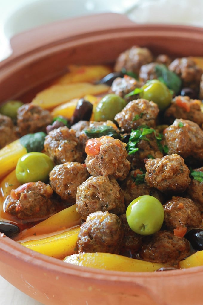 Tajine aux boulettes de viande, pommes de terre et olives. Le tout est cuit dans une sauce tomate. Si vous n'avez pas de tajine en terre cuite, pas de problème. Utilisez une cocotte ou une grande poêle avec couvercle. Un plat simple, complet et réconfortant.