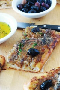 Morceau de pissaladière niçoise avec pissalat oignon et olives sur une planche à découper