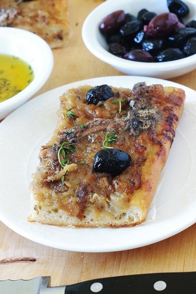 La pissaladière, une recette niçoise avec une pâte à pain ou à pizza, oignons confits et ail, anchois et olives, des herbes aromatiques. Un régal pour les amateurs d’oignons et d’anchois. Dégustez-la chaude ou froide. Avec une petite salade, cela vous fait un bon plat complet.