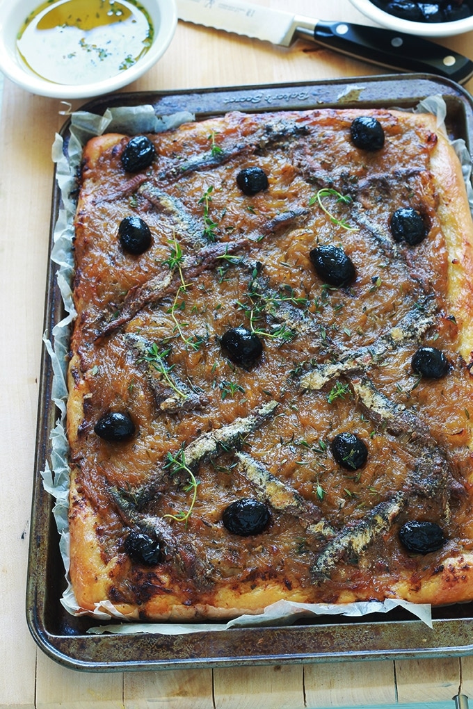 La pissaladière, une recette niçoise avec une pâte à pain ou à pizza, oignons confits et ail, anchois et olives, des herbes aromatiques. Un régal pour les amateurs d’oignons et d’anchois. Dégustez-la chaude ou froide. Avec une petite salade, cela vous fait un bon plat complet.