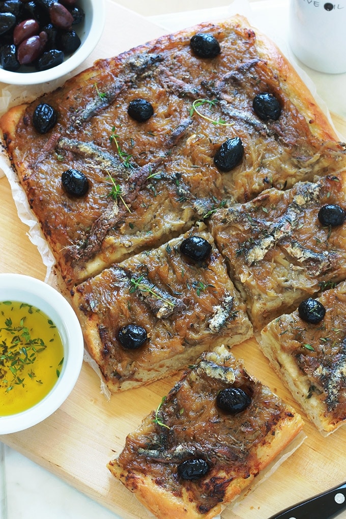 La pissaladière, une recette niçoise avec une pâte à pain ou à pizza, oignons confits et ail, anchois et olives, des herbes aromatiques. Un régal pour les amateurs d’oignons et d’anchois. Dégustez-la chaude ou froide. Avec une petite salade, cela vous fait un bon plat complet.