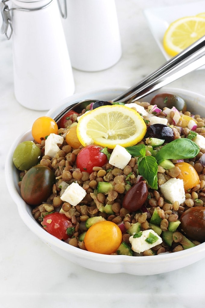 Salade de lentilles à la grecque, facile, très rapide et pleine de saveurs. Composée de lentilles, tomates, feta, concombre, oignons et olives, le tout arrosé d'une vinaigrette citronnée parfumée aux herbes aromatiques.