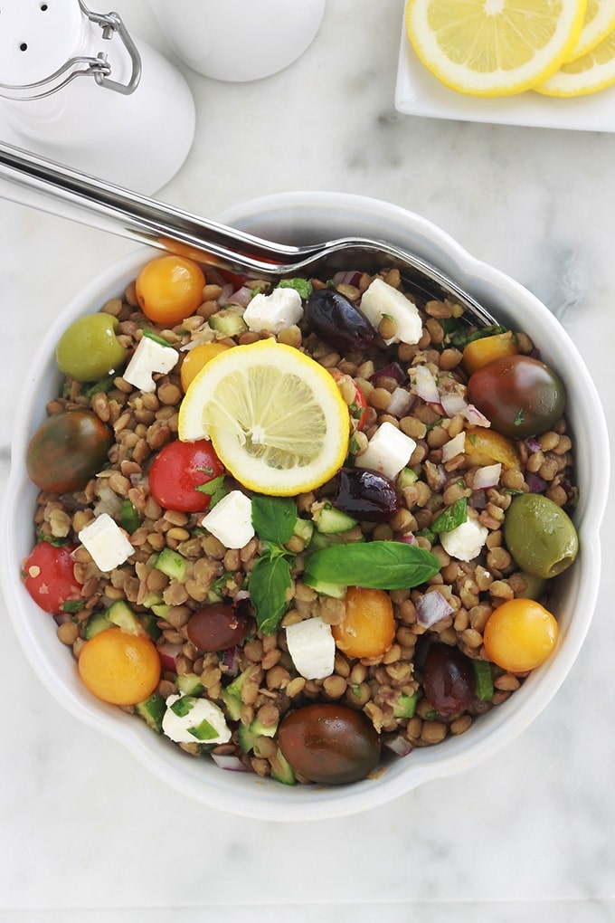 Salade de lentilles à la grecque, facile, très rapide et pleine de saveurs. Composée de lentilles, tomates, feta, concombre, oignons et olives, le tout arrosé d'une vinaigrette citronnée parfumée aux herbes aromatiques.