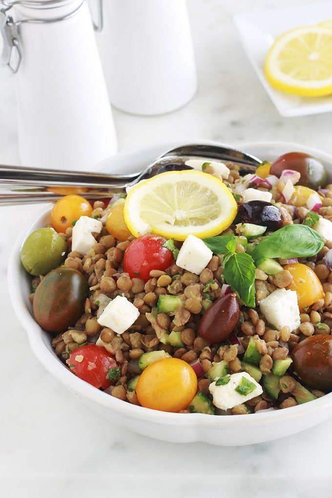 Salade de lentilles à la grecque, facile, très rapide et pleine de saveurs. Composée de lentilles, tomates, feta, concombre, oignons et olives, le tout arrosé d'une vinaigrette citronnée parfumée aux herbes aromatiques.