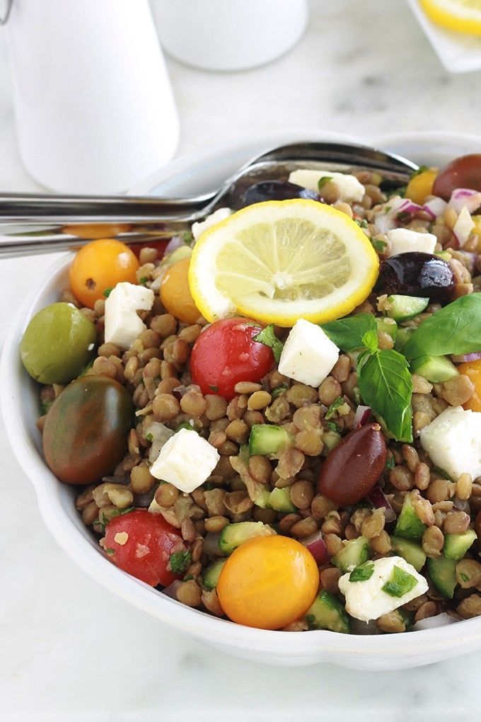 Salade de lentilles à la grecque, facile, très rapide et pleine de saveurs. Composée de lentilles, tomates, feta, concombre, oignons et olives, le tout arrosé d'une vinaigrette citronnée parfumée aux herbes aromatiques.