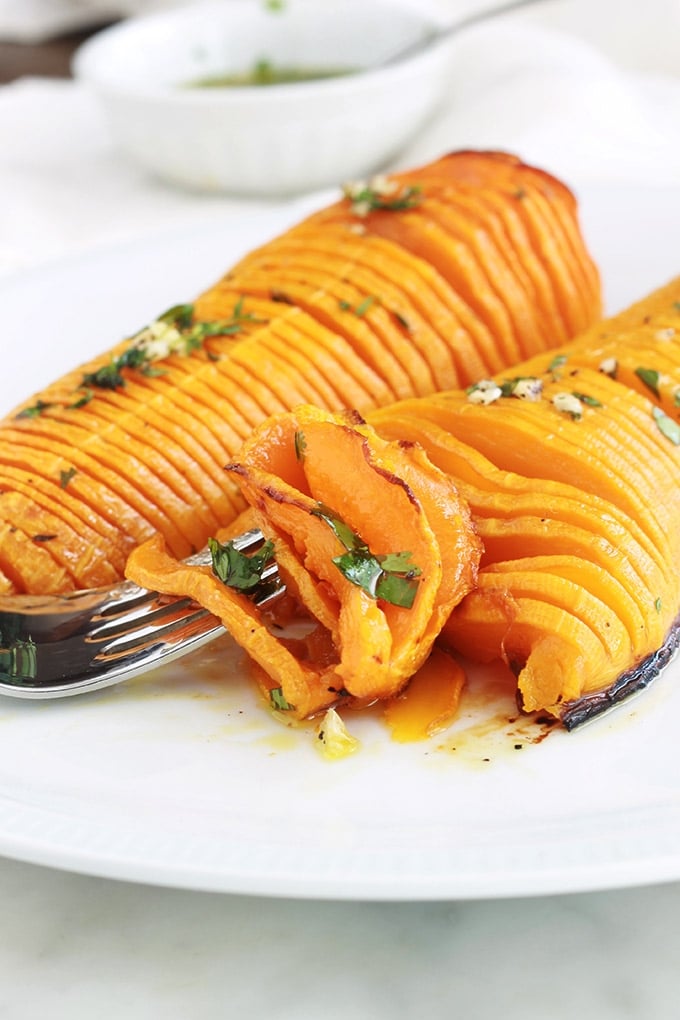 Voici une recette originale de courge butternut rôtie au four : à la hasselback! Simple et facile à faire. Ce sont des demi courges butternut (doubeurre) coupées en tranches (sans aller jusqu’au bout), assaisonnées avec des épices, herbes aromatiques et huile d’olive puis rôties au four. 