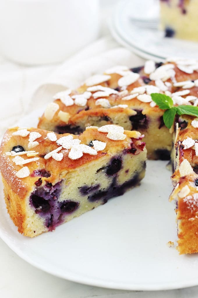 Encore un gâteau au yaourt hyper moelleux, aux myrtilles (ou bleuets) et amandes! Pot de yaourt (nature ou parfumé), myrtilles (fraîches, congelées ou au sirop), poudre d’amande et des amandes effilées. Une recette facile, gâteau gourmand et trop bon!