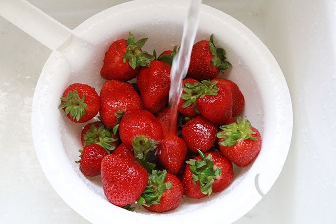 Fraises fraiches dans une passoire sous l'eau du robinet