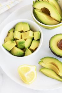 Chair d'avocat coupée en tranches et en des dans de petits bols, demi avocat et citron pour eviter que ça noircisse