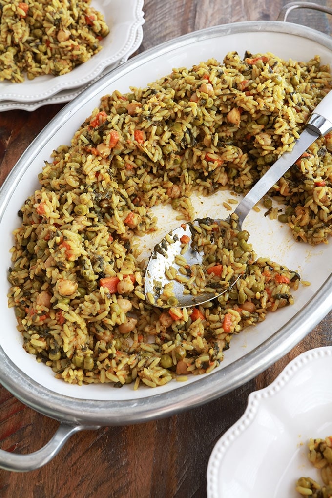 Riz aux légumes cuits à la vapeur servi dans un grand plat (pois chiches, épinards, petits pois, carottes, oignons, ail, épices, huile d'olive)