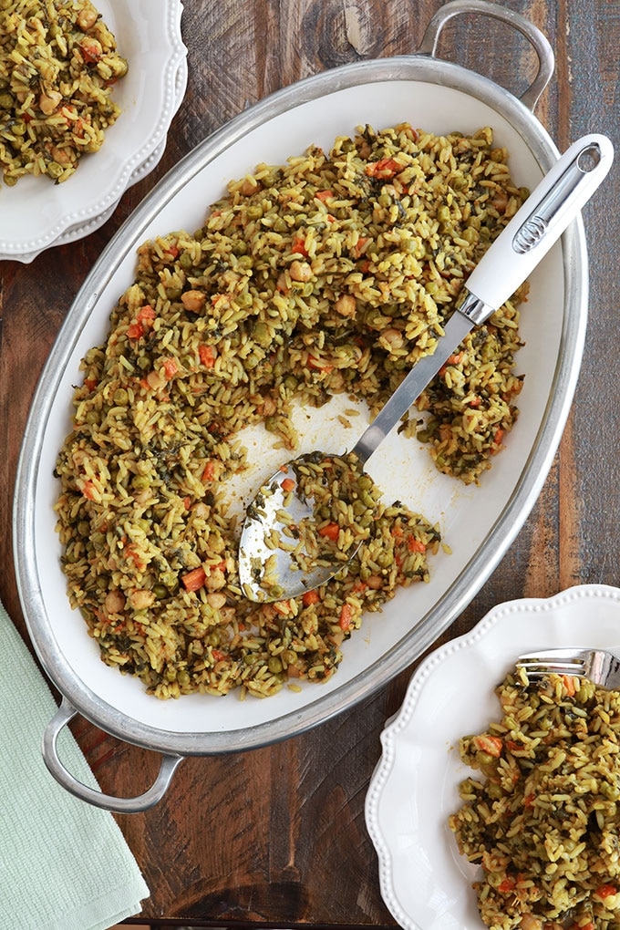 Riz aux légumes cuits à la vapeur servi dans un grand plat (pois chiches, épinards, petits pois, carottes, oignons, ail, épices, huile d'olive)