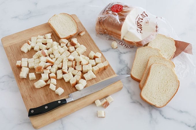 Pain de mie coupé en cubes sur une planche à découper