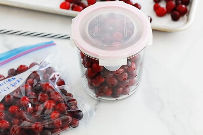Cranberries (ou canneberges, atocas) fraîches pré-congelées dans un bocal en verre et un sac type congélation dont l'air est vidé en utilisant une paille.