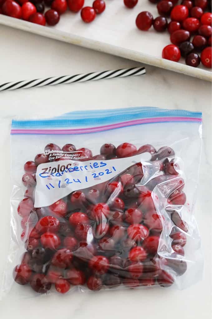 Cranberries (canneberges ou atocas) pré-congelées dans un sac de congélation dont l'air est vidé avec une paille