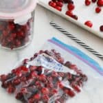 Canneberges fraiches ou cranberries dans un sac special congelation dont l'air est vide avec une paille, bocal et plaque.