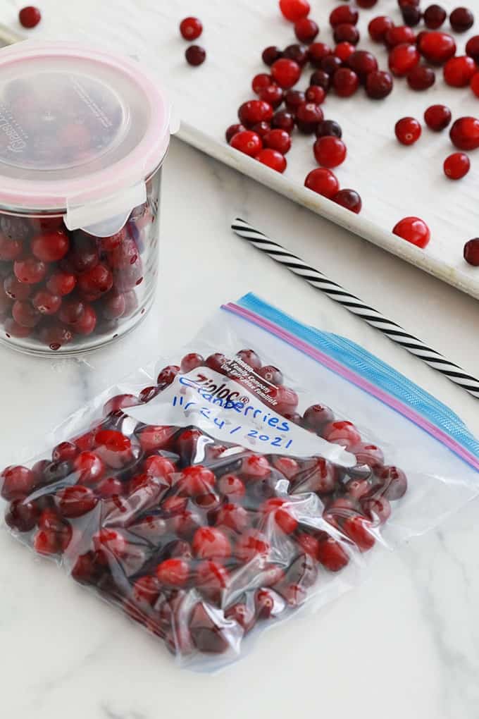Canneberges fraiches ou cranberries dans un sac special congelation dont l'air est vide avec une paille, bocal et plaque.