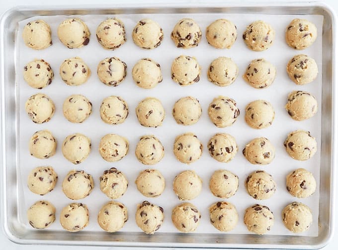 Boules de pâte à cookies crue sur une plaque à pâtisserie tapissée de papier sulfurisé (papier parchemin)