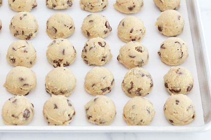 Boules de pâte à cookies aux pépites de chocolat fermes et solides sur une plaque prêtes à être congelées