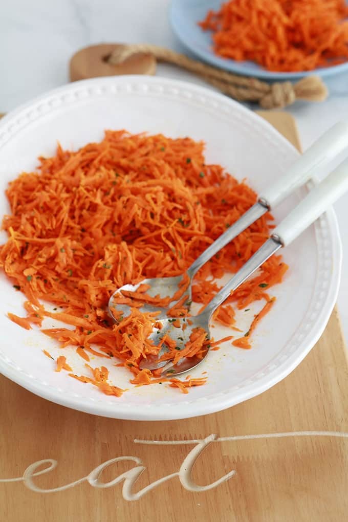 Salade de carottes râpées assaisonée de vinaigrette dans un plat de service