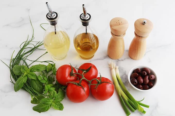 Ingrédients de la salade de tomate simple : Tomates, herbes aromatiques fraîches, oignons verts, olives, huile, vinaigre, sel et poivre