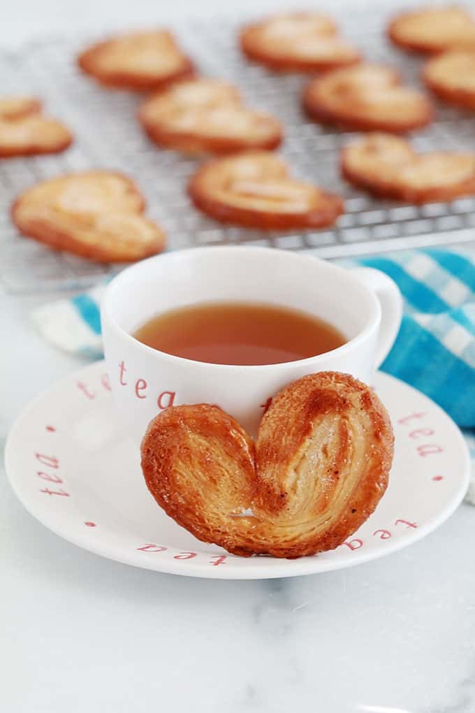 Palmiers, biscuits sucrés feuilletés sur une grille et une tasse de thé