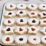 Sur un grand plateau, des biscuits sablés de Noel à la confiture de framboise et confiture d'abricot.