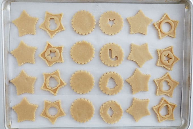 Dans une plaque allant au four, des biscuits sables linzer crus en formes de Noel (avant cuisson).