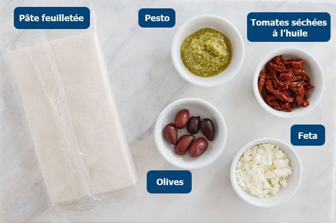 Les Ingrédients des palmiers feuilletés pour apéro : pesto, tomates séchées, feta émietté et olives