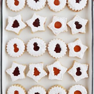 Sur un grand plateau, des biscuits sablés de Noel à la confiture de framboise et confiture d'abricot.