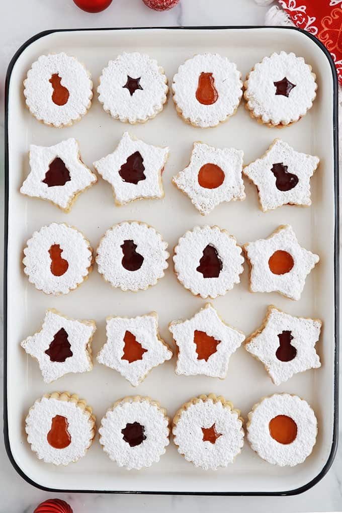 Sur un grand plateau, des biscuits sablés de Noel à la confiture de framboise et confiture d'abricot.