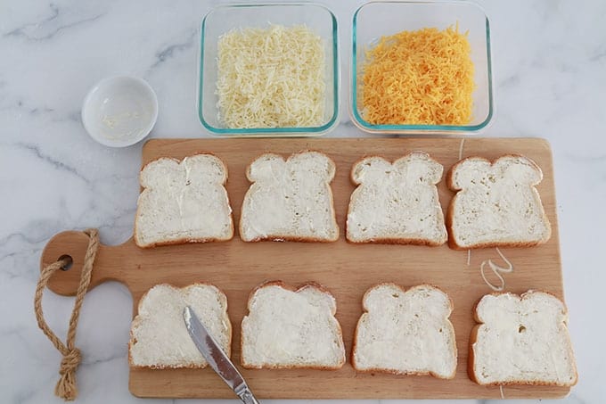Sur un plan de travail : 8 tranches de pain de mie beurrées, du fromage râpé dans deux contenants.