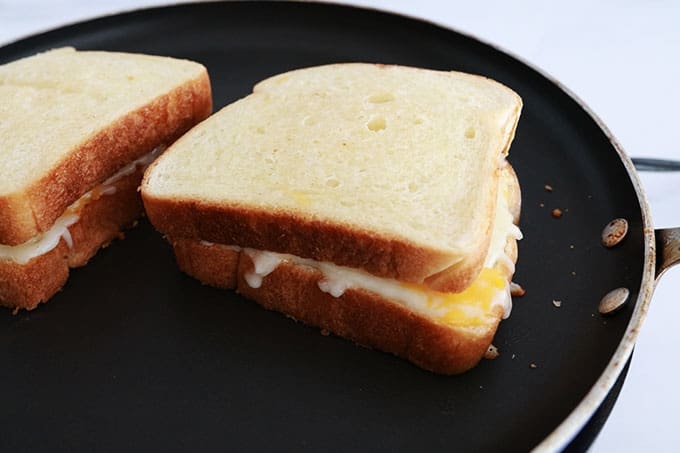 Sandwich Grilled Cheese dans une poêle, avec du fromage qui fond à l'intérieur.
