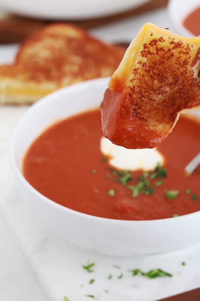 Soupe de tomate maison dans un bol et sandwich au fromage fondu.