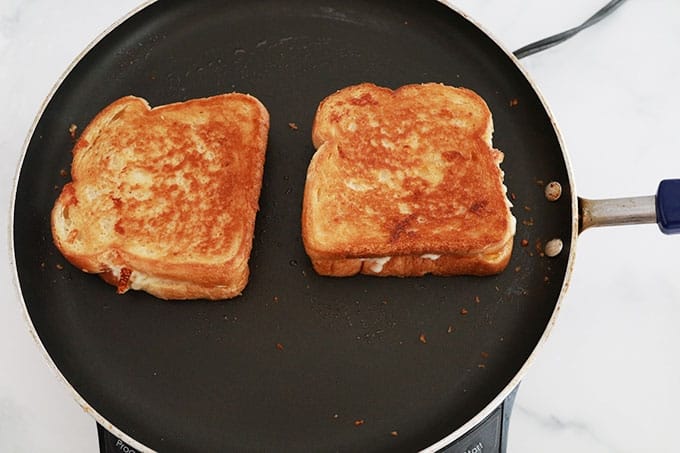 Deux sandwichs grilled cheese dans une poêle.