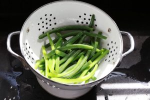 Haricots verts frais blanchis égouttés dans une passoire.