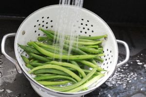 Haricots verts frais lavés sous l'eau du robinet.